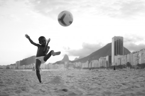 BRAZIL. Rio de Janeiro. 2014. Daniel Eliseu, 6, tees up for “target practice” with his father as the coachtarget. Little Daniel is from the nearby community Babilônia. © David Alan HarveyMagnum Photos