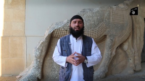 Un miliziano dell'ISIS, davanti a un antico bassorilievo