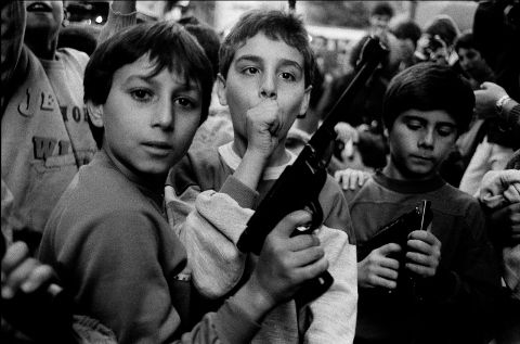 Letizia Battaglia, Festa del giorno dei morti. I bambini giocano con le armi, Palermo, 1986, Courtesy l'artista