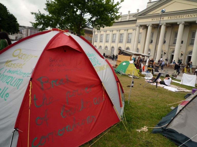 Friedrichsplatz Kassel – »doccupy« movement 4 La “d” come documenta, ma anche come d-Occupy. Il movimento pervade la rassegna di Kassel, Carolyn Christov-Bakargiev lo accoglie. E un po’ lo irreggimenta…