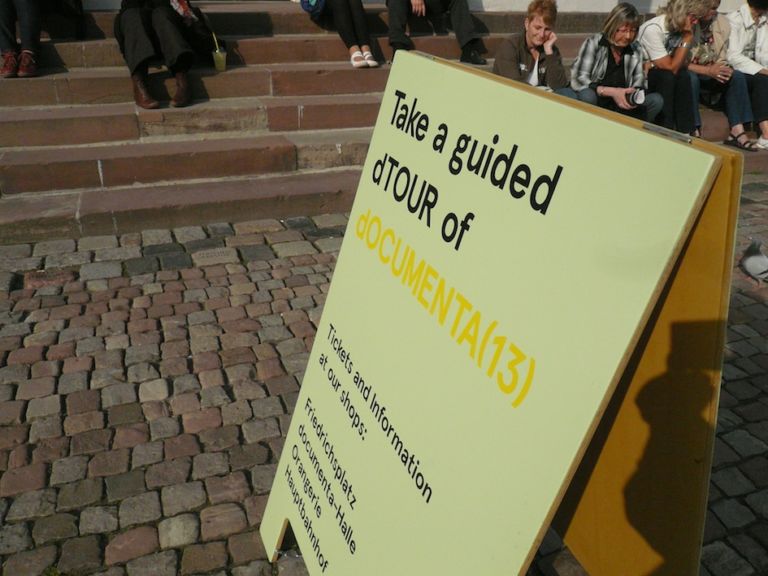 dOCUMENTA 13 – punto info e biglietti per dTOURS Frierdrichsplatz La “d” come documenta, ma anche come d-Occupy. Il movimento pervade la rassegna di Kassel, Carolyn Christov-Bakargiev lo accoglie. E un po’ lo irreggimenta…