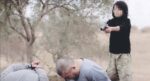 Uno still dal video in cui un ragazzino dell'ISIS spara ai prigionieri kazaki