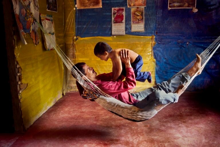 Steve McCurry, A farmer and his son play in a hammock at home, La Esperanza, Colombia, 2004