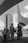A worker from Nordeste shows his family the new city on inauguration day. In the background: the National Congress building by Oscar Niemeyer. Brasilia, Brazil, 1960 © René Burri / Magnum Photos