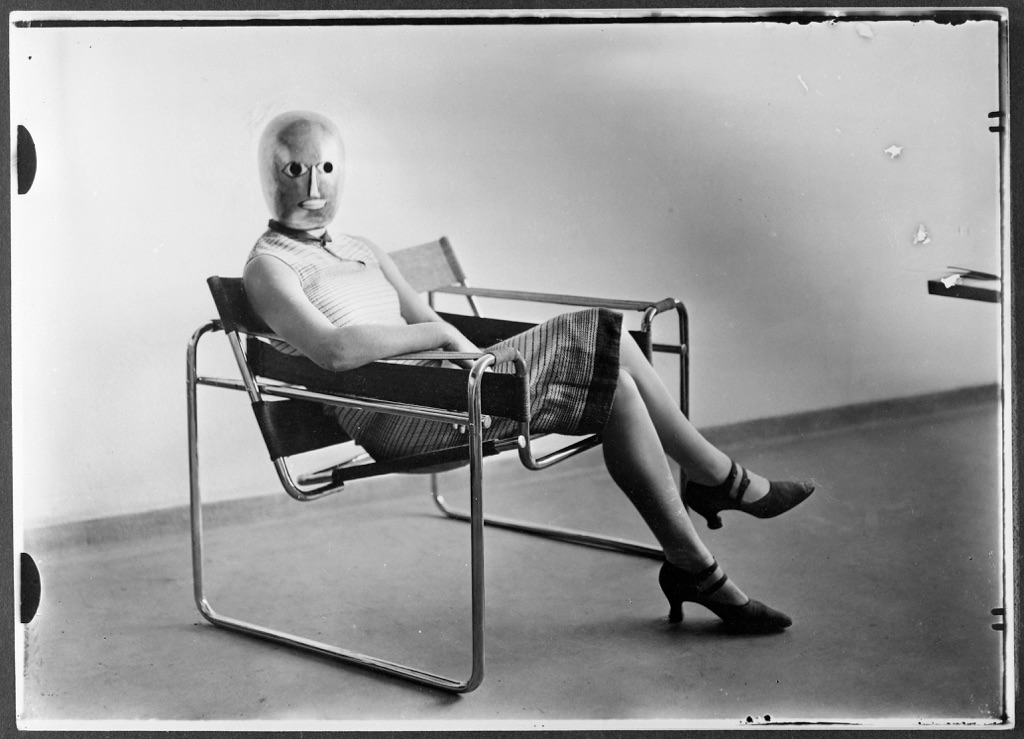 Erich Consemüller, Scena dal Bauhaus. Sconosciuta su una poltrona tubolare di Marcel Breuer con indosso una maschera di Oskar Schlemmer e un abito di Lis Beyer, 1926 © Bauhaus-Archiv Berlin