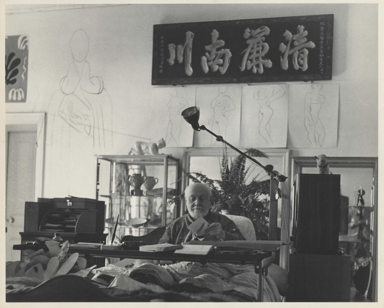 Matisse_MFA_AA. Photograph by Philippe Halsam of Matisse working on a cut-out under his Chinese calligraphy panel