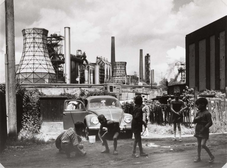 Rudolf Holtappel (Münster, Germania, 1923 – Duisburg, Germania, 2013), Duisburg Bruckhausen, Ebertstrasse con stabilimento metallurgico August Thyssen, 1968, Stampa ai sali d’argento, Estate of the Artist