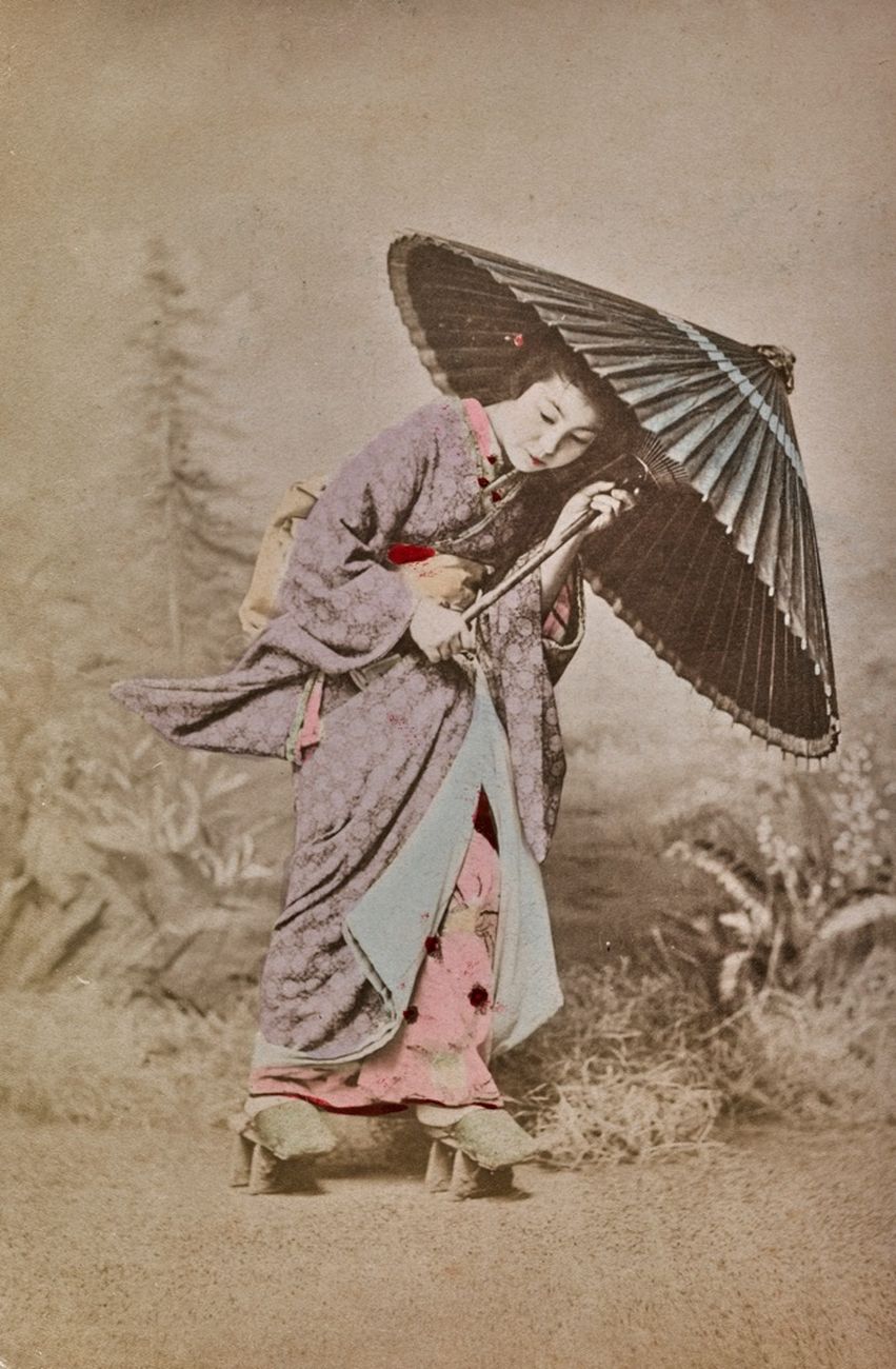 Una geisha cammina sfidando il vento con il suo ombrellino. 1870-1890, stampa all’albumina dipinta a mano, © Archivi Alinari, Firenze