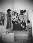 Peggy Guggenheim durante l’allestimento del padiglione greco con Interno olandese II (1928) e Donna seduta II (1939) di Joan Miró, XXIV Biennale di Venezia, 1948. Solomon R. Guggenheim Foundation, Venice, photo Archivio Cameraphoto Epoche