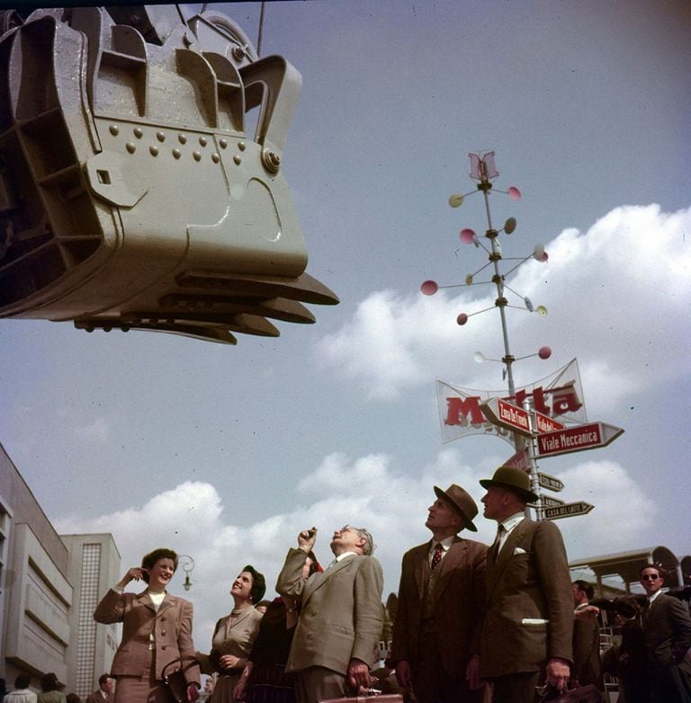 1953. Escavatore in esposizione alla Fiera Campionaria di Milano. Alle spalle dei visitatori installazione pubblicitaria Motta, progetto di Bruno Munari. Courtesy La Triennale di Milano