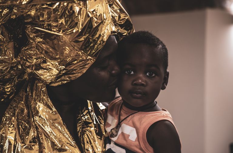 Silent Academy collezione Emergency Blanket Matera 2019. Tessy con suo figlio Harrys. Ph. Pietro Micucci Migranti e integrazione: il ruolo della cultura. Due storie da Matera 2019