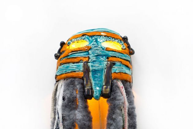 Giusy Pirrotta, Maschera Bahati (fortuna), ceramica smaltata, lampadina colorata, tenda di ciniglia, cotone, 2019