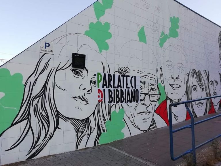 Il muro di Lucamaleonte a Ostia, sfregiato da un manifesto di Casapound su Bibbiano