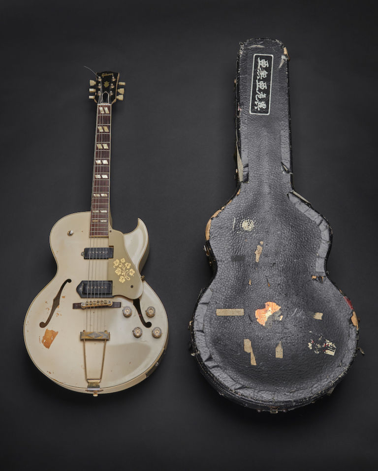 A 1950S GIBSON ES-295 with a white finish inside a hardshell contour case with orange plush lining. The guitar was used by Mick Jones during recording of the London Calling album and in the music video for the title track of the album, released as a single in December 1979. © The Clash