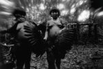 Claudia Andujar, Candinha and Mariazinha Korihana thëri clean red billed curassow, whose plumage is used to feather arrows, Catrimani, Roraima, 1974