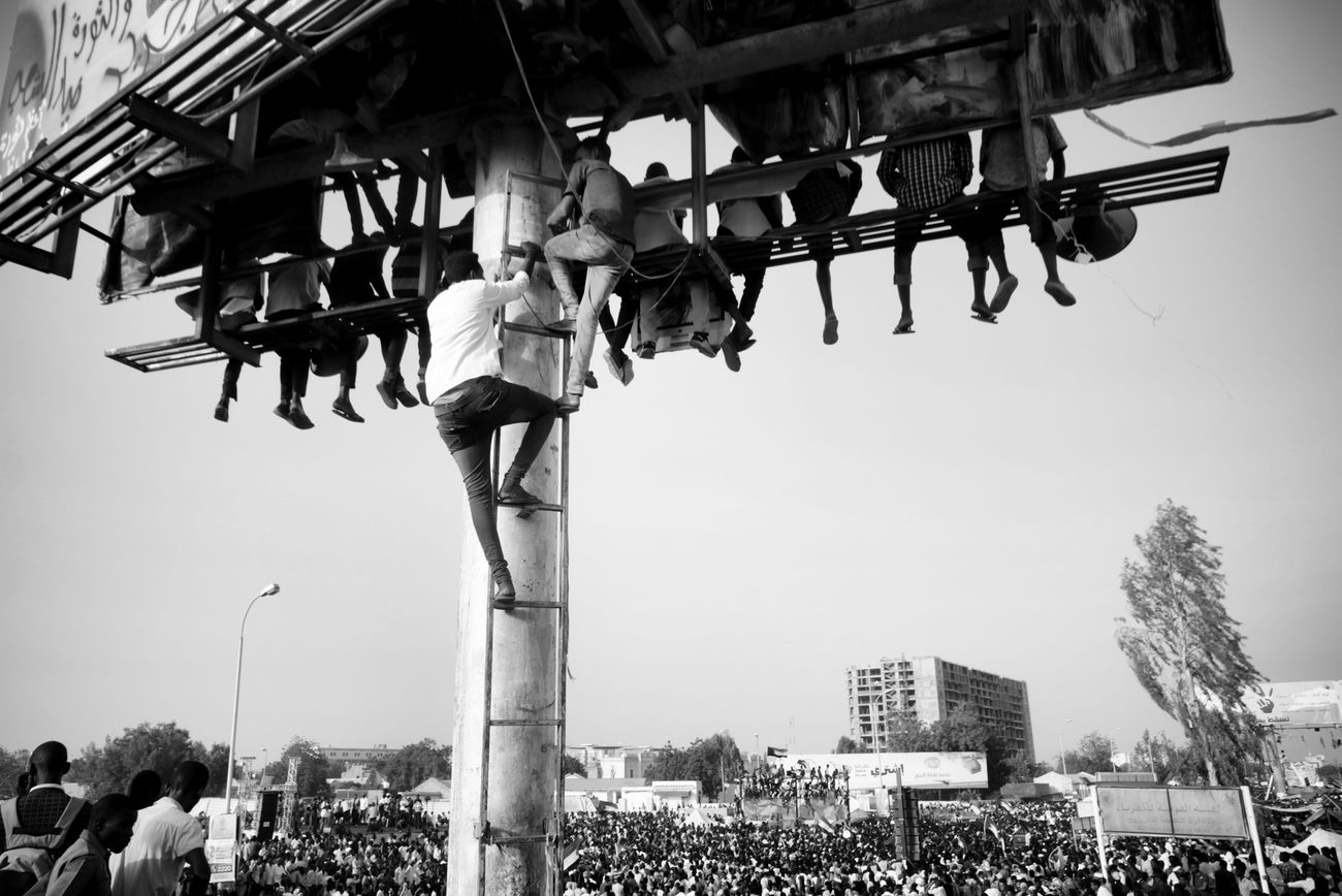 Ahmed Ano, Des civils escaladent d’énormes panneaux publicitaires pour crier « Liberté, paix et justice ». Sit in, quartier général militaire, Khartoum, 19 avril 2019