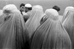 MAN STANDS IN THE MIDDLE OF A FLOCK OF DOVES AT THE HAZRAT ALI MOSQUE BY STEVE MCCURRY