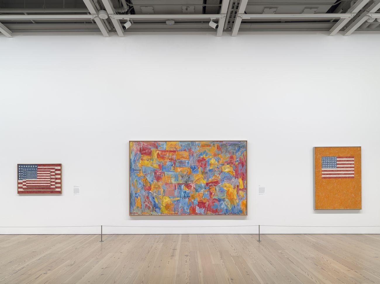 Installation view of Jasper Johns: Mind/Mirror (Whitney Museum of American Art, New York, September 29, 2021-February 13, 2022). From left to right: Three Flags, 1958; Map, 1961; Flag on Orange Field, 1957. Photograph by Ron Amstutz