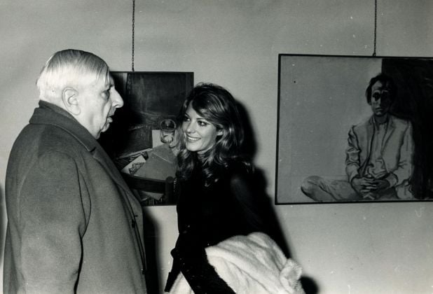 Giorgio de Chirico e Simona Marchini all'inaugurazione della mostra di Renato Guttuso, 5 marzo 1969. Sulla destra, il Ritratto di Mario Schifano, 1966