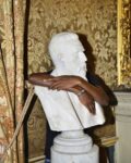 Sangare Moussa, Malian rap singer and an asylum seeker, behind the statue of Nicolò Turrisi Colonna, mayor of Palermo from 1880 to 1887. Photograph taken behind the scenes of «Un giorno, questi volti» a film by Martino Lo Cascio. «Golden Room», Palermo dal 1880 al 1887, ph Nicola Lo Calzo