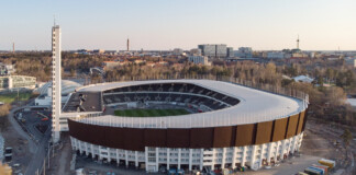 Joneikifi, Aerial view of Helsinki Olympic Stadium under renovation with the new Pasila district skyline in the background, fonte Wikipedia, CC BY SA 4.0