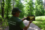 Una guida mostra la riproduzione di un'opera nel luogo dove fu dipinta, Foresta di Fontainebleau presso Barbizon, Francia. Photo © Dario Bragaglia