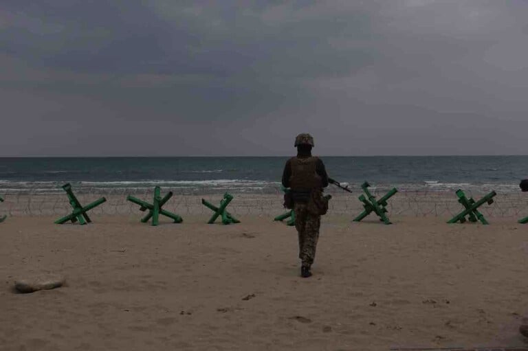 David Grigoryan A soldier guarding the coastline mined and blocked by wire and Czech hedgehogs, Odessa 2022 Serie Odessa Sole mio, 2022 © David Grigoryan Courtesy zanzara arte contemporanea