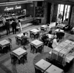 Stazione di Bologna Centrale. Sala del ristorante della stazione con viaggiatori in piedi al banco liquori e viaggiatori seduti ai tavoli, Autore: Josip Ciganovic, Data: 1957, Fondazione FS Italiane