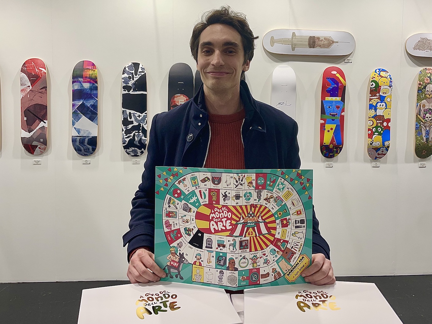 Giulio Alvigini con il suo gioco da tavolo Il Giro del Mondo dell'Arte allo stand della galleria Bonobolabo, (un)fair 2023, Milano, foto di Alberto Villa