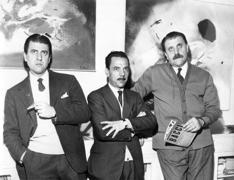 Renato Cardazzo, Edmondo Bacci e Carlo Cardazzo (da sinistra) in occasione della mostra di Bacci alla Galleria del Naviglio, Milano, 1957. Alle loro spalle, da sinistra, Avvenimento #255 (1957 c.) e Avvenimento #233 (1957 c.). Archivio Edmondo Bacci, Venice