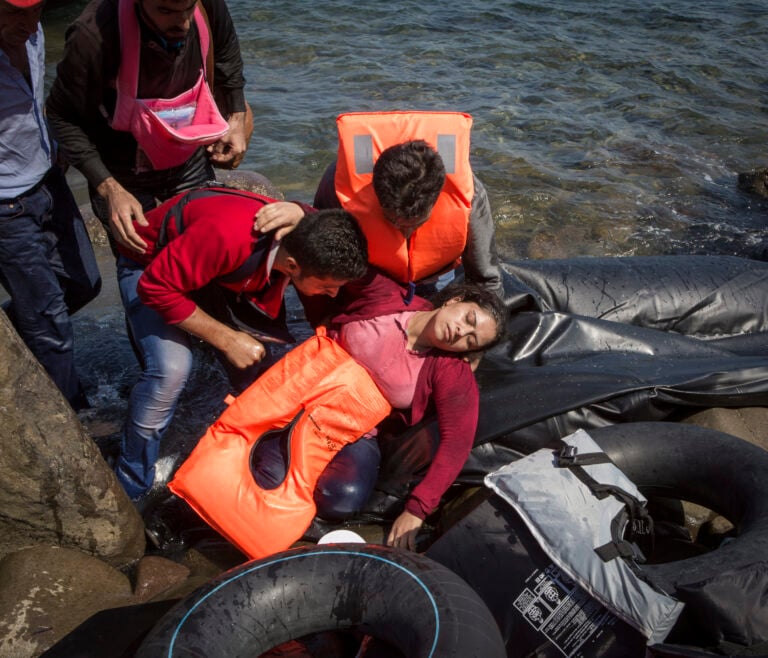 Ivor Prickett. Susan, rifugiata siriana di trentacinque anni originaria di Aleppo, sviene a causa del mal di mare e della fatica dopo aver attraversato l’Egeo dalla Turchia a Lesbo con il marito e i tre bambini. 2015, Lesbo, Grecia. Fotografia dalla serie "Seeking Shelter. Part II - West". Courtesy and © Ivor Prickett