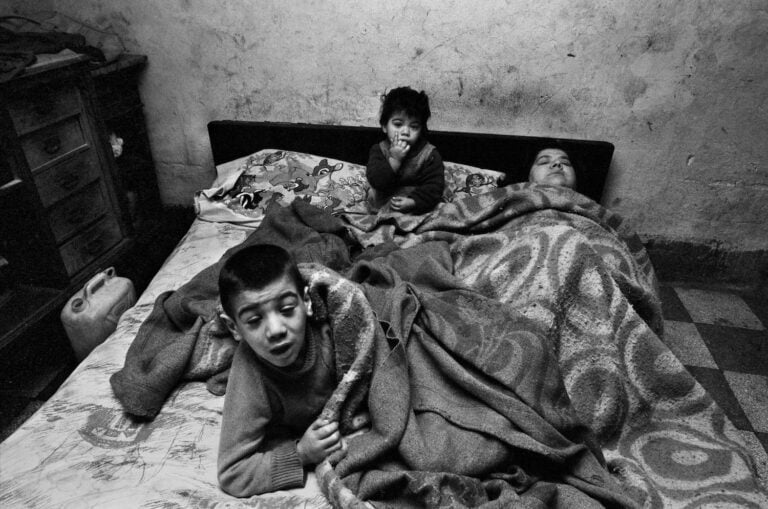 La donna e i suoi bambini stanno sempre a letto. In casa non ci sono né luce né acqua. Palermo, 1978 ©Archivio Letizia Battaglia