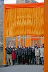 Christo and Jeanne-Claude with Mayor Michael Bloomberg, who opens a gate's cocoon to unfurl the first fabric panel New York City, February 12, 2005 — Photo: Wolfgang Volz © 2005 Christo and Jeanne-Claude Foundation