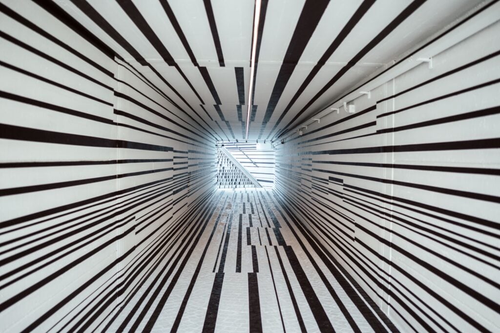 L’opera d’arte optical di Esther Stocker copre i murales di un sottopasso. Arte pubblica, polemiche e riqualificazione a Trento