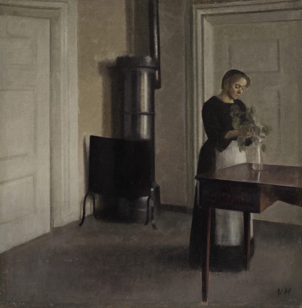 Vilhelm Hammersh&oslash;i, Interior of Woman Placing Branches in Vase on Table, 1900. Courtesy Phillips