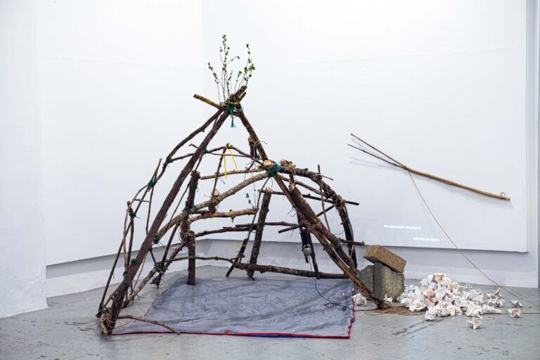 Simone Marconi, Hiding From a Self I Am No Longer, 2025, legno, audio, elastici, corde, iuta, cuffie, proiezione video, sacco a pelo, cemento, carta, gessetto, 260 x 240 x 180 cm, 13&rsquo;